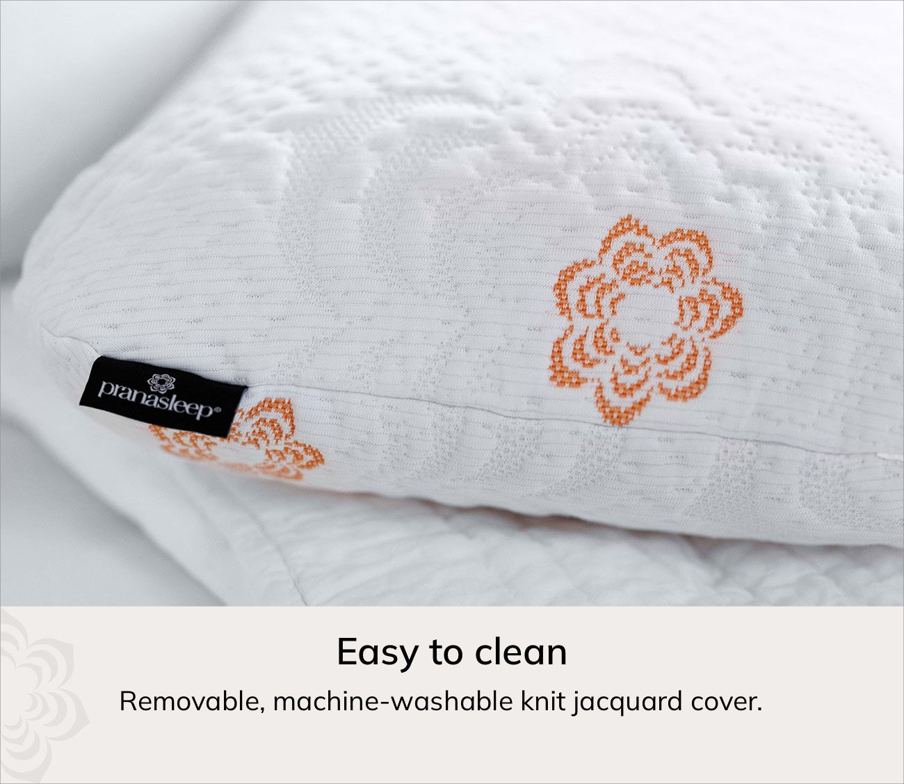 A close-up of Karma cooling pillow with an orange floral embroidered pattern and a black Paraiso Sleep brand tag. Text at the bottom reads 'Easy to clean' and 'Removable, machine-washable knit jacquard cover.