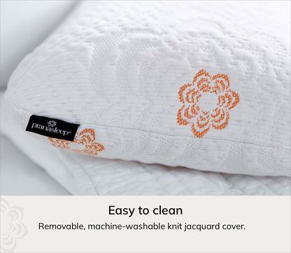 A close-up of Karma cooling pillow with an orange floral embroidered pattern and a black Paraiso Sleep brand tag. Text at the bottom reads 'Easy to clean' and 'Removable, machine-washable knit jacquard cover.