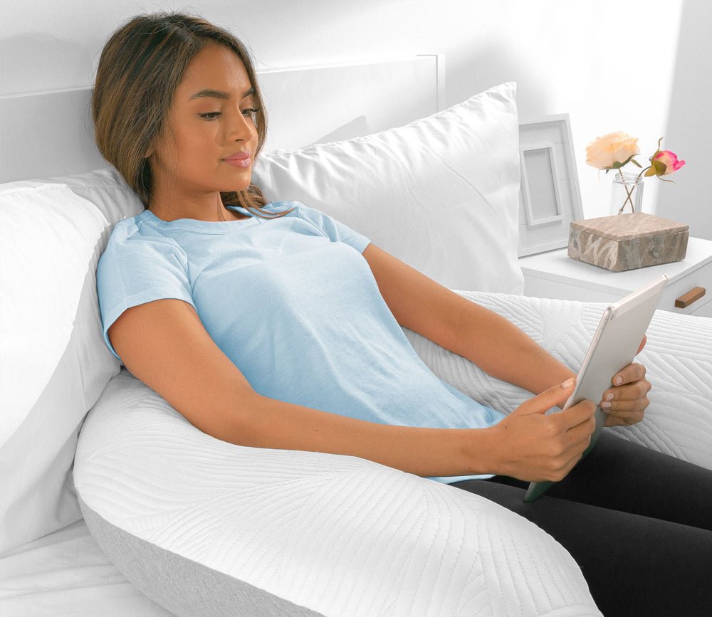 Girl sitting up in bed, reading with the Bedgear Dual - Sided U - Shaped Body Pillow by Bedgear