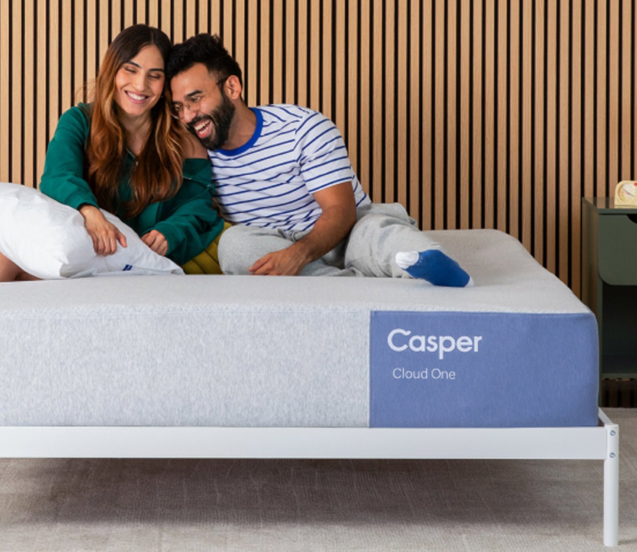 Woman and man resting and smiling on top of Casper Cloud One Mattress.