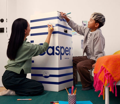 Woman and child drawing on Casper Snug Kid's Mattress delivery box