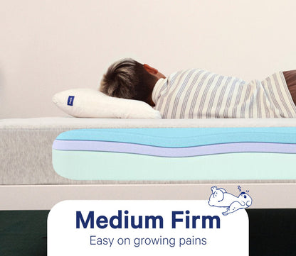 Child resting on Casper Snug Kid's Mattress showcasing medium firm comfort.