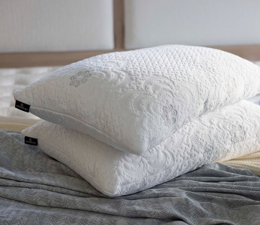 Two PranaSleep Dharma Adjustable Latex Pillows stacked on a bed, showcasing their textured knit covers and premium design.