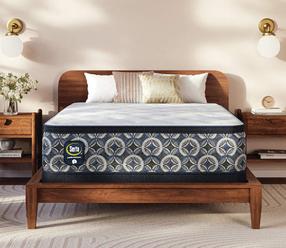 Serta Perfect Sleeper mattress with a quilted white sleep surface and patterned blue side panels displayed on a wooden platform bed in a modern bedroom.